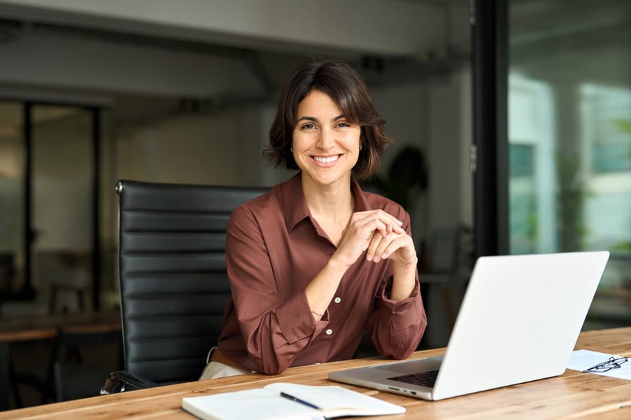 A confident business woman sits in front of her laptop.