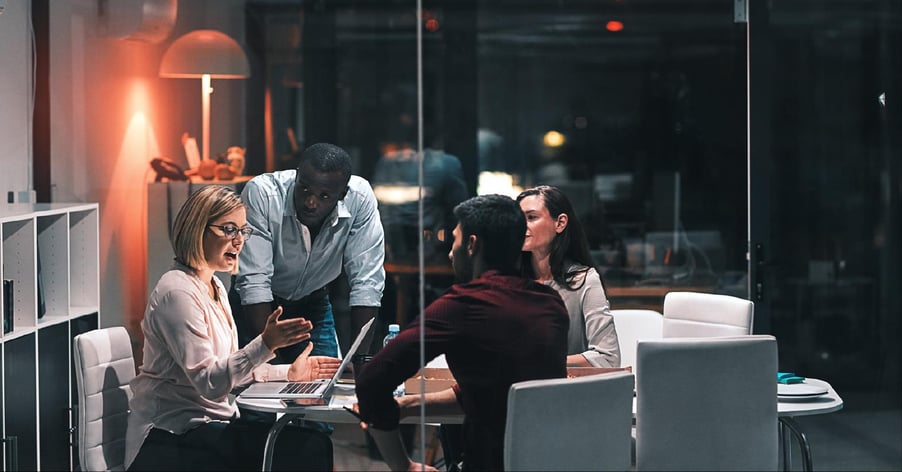 A team discusses a strategic plan after hours at a round table.