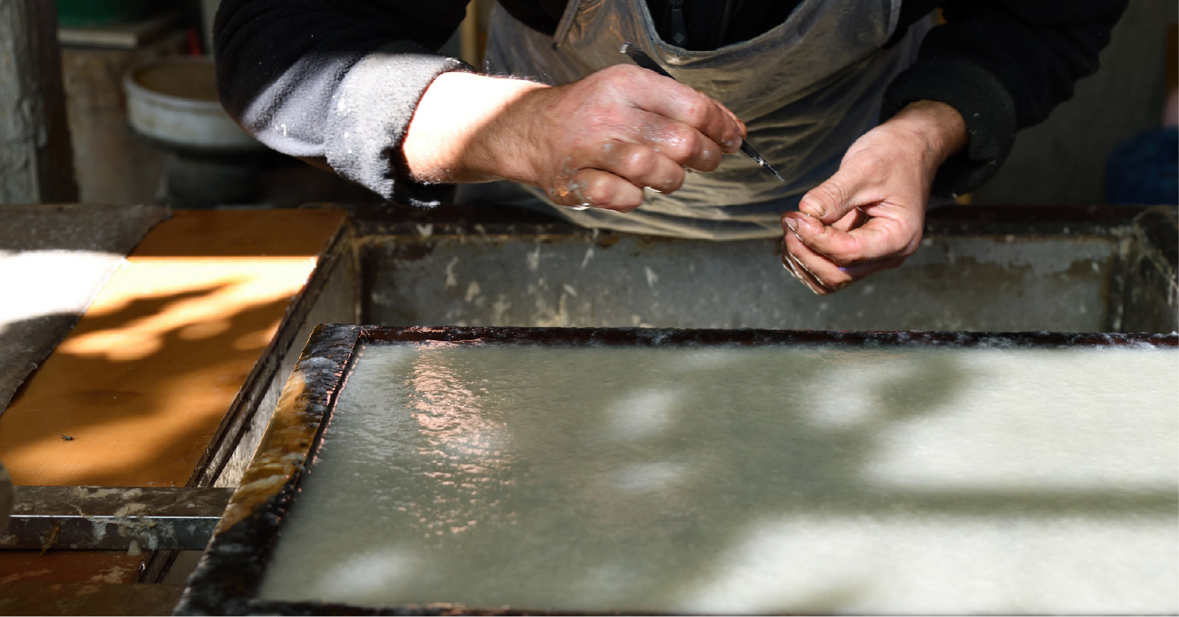 A man makes paper using traditional techniques.