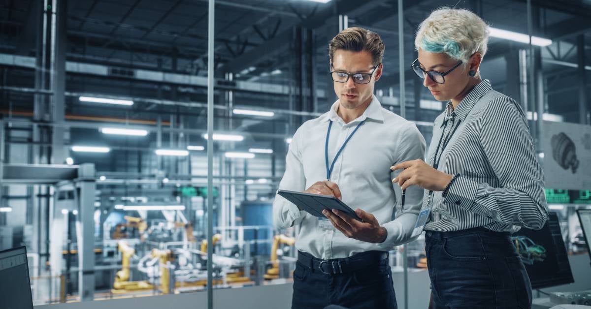 Two factory workers looking at a tablet