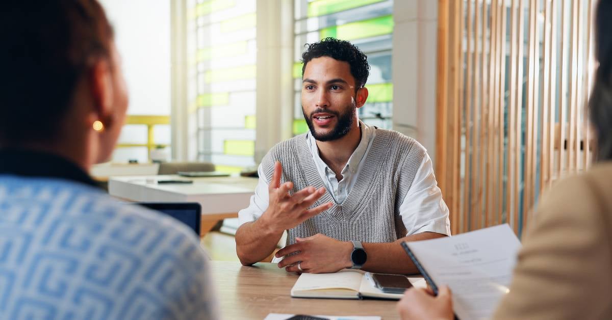 A male professional meets with two business executives.