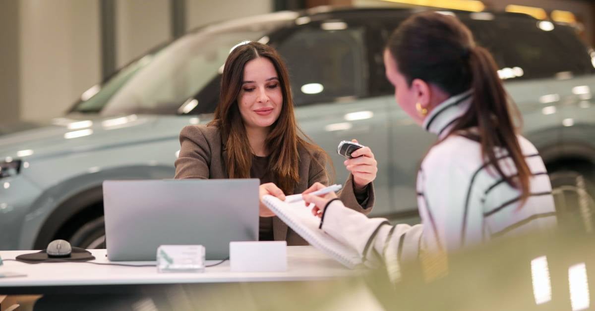 Two women discuss financing options at a car dealership.
