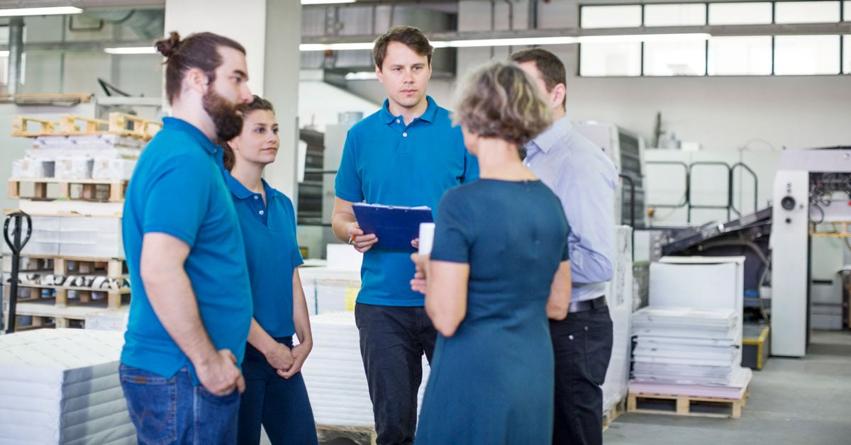Professional printers having a discussion surrounded by packaging materials.