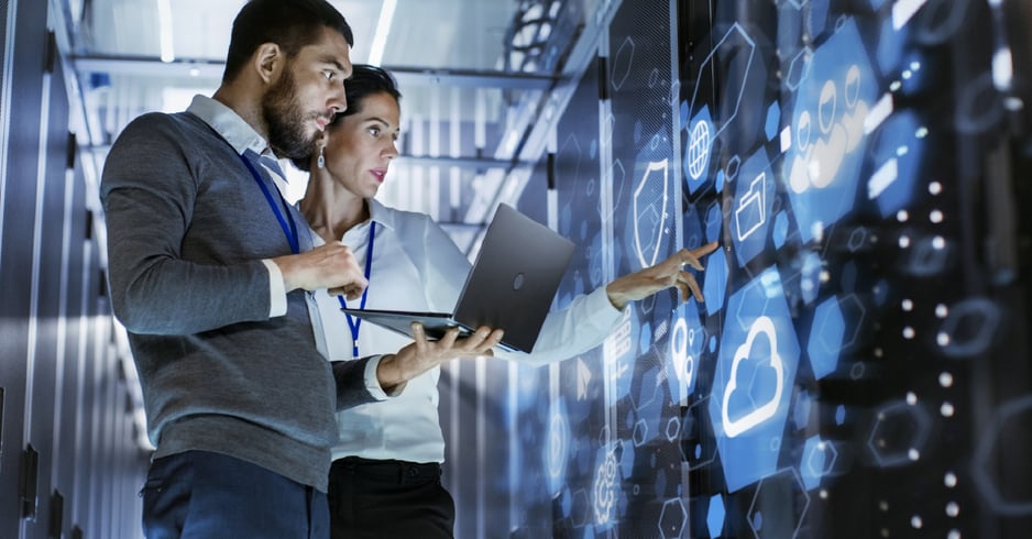 Male and female IT pros view a digitized depiction of their network's security and performance.