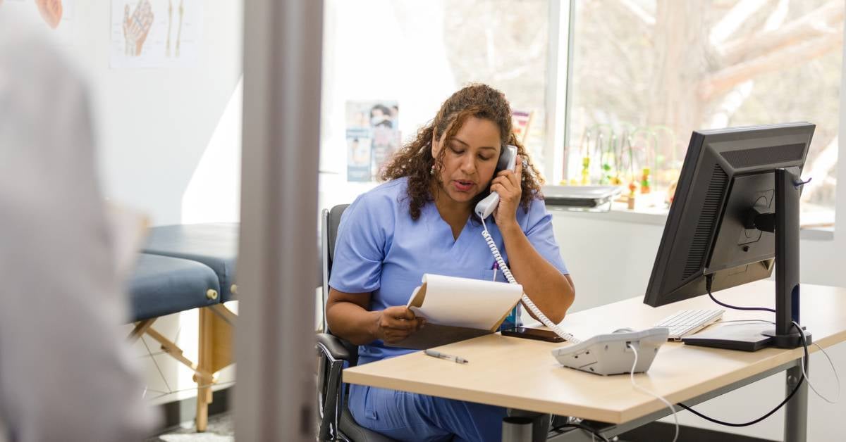 A healthcare worker using her medical office phone system.
