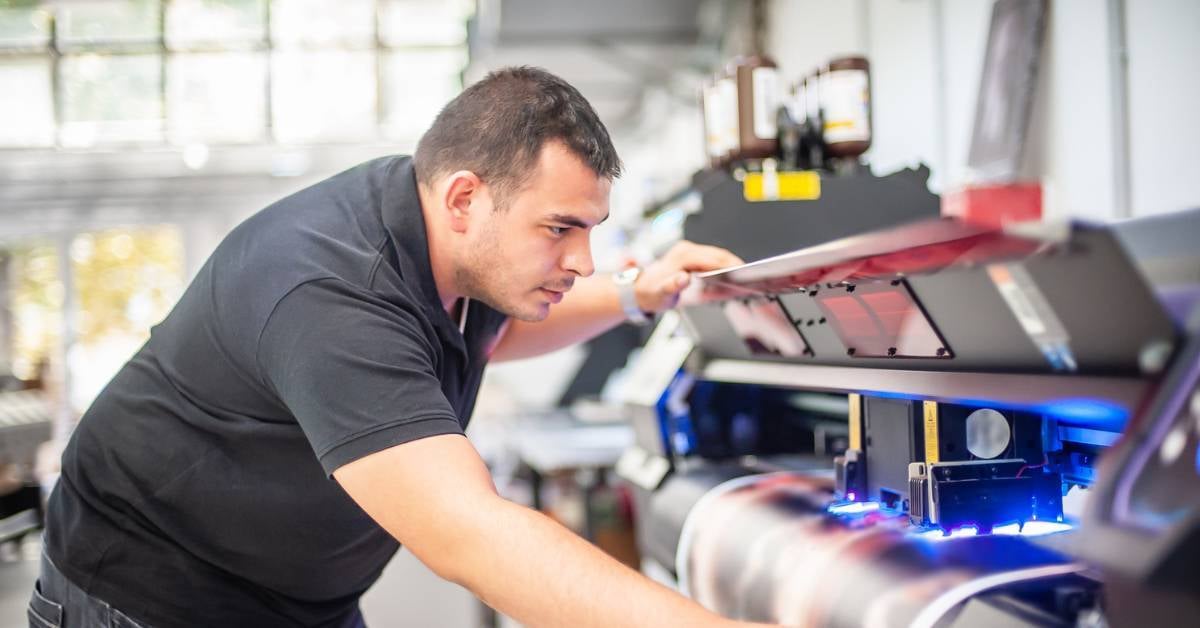 A professional print tech works on a wide format printer.