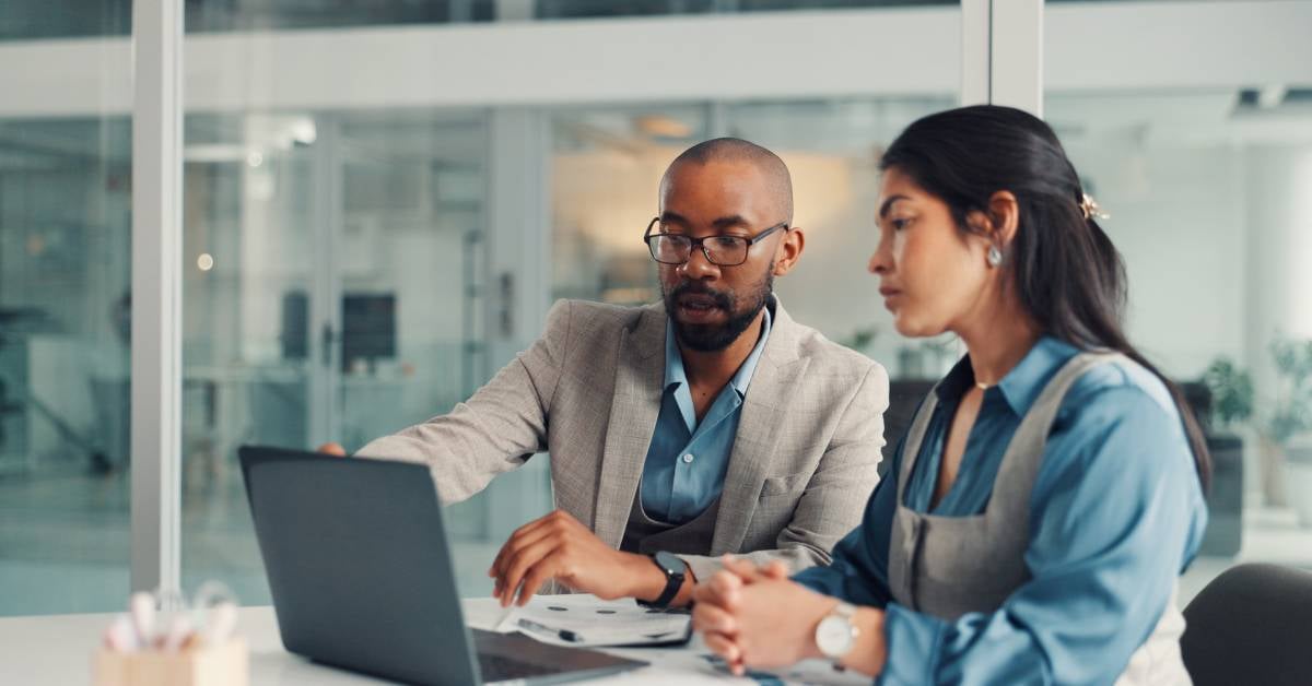 Two executives collaborating on a laptop. 
