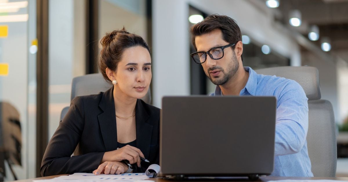 Two coworkers looking at a laptop.