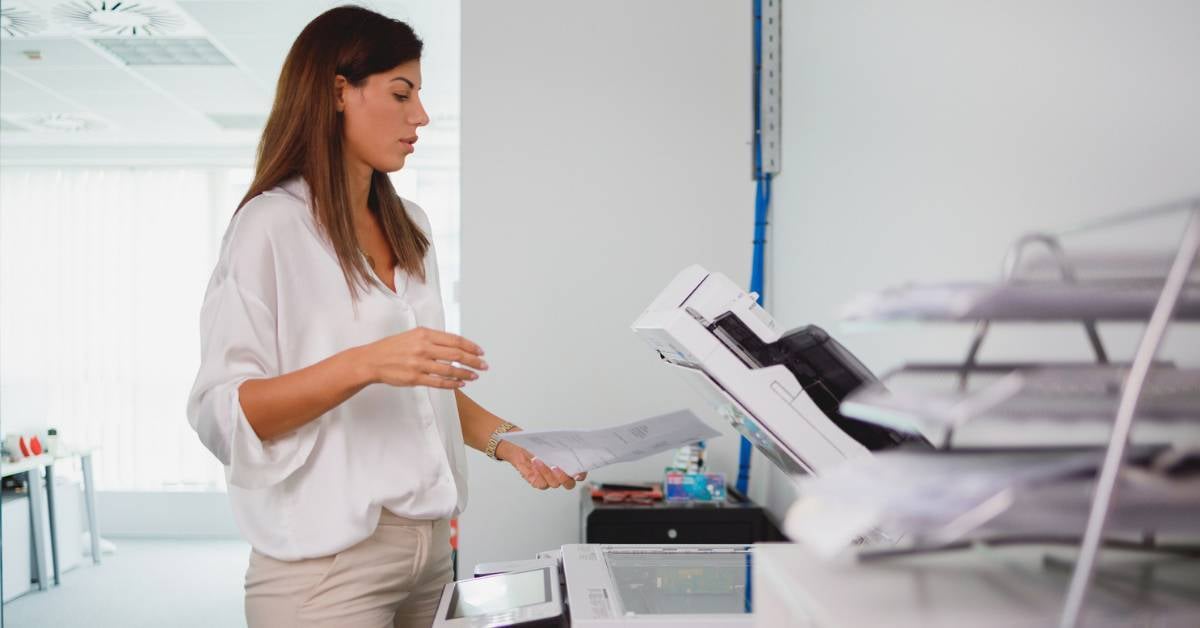 A woman uses a printer in a healthcare setting.