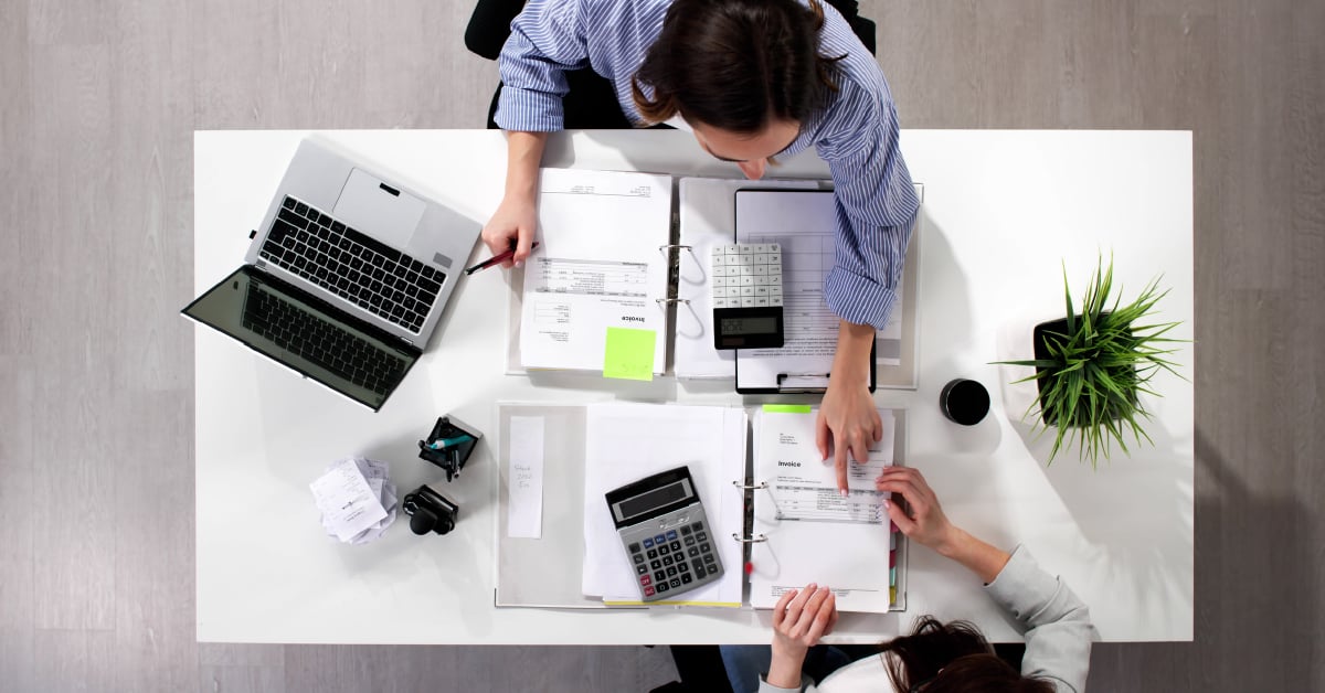 An overhead view of two employees looking over their budget.