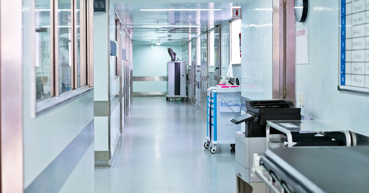 A hospital hallway with medical equipment and a business printer.