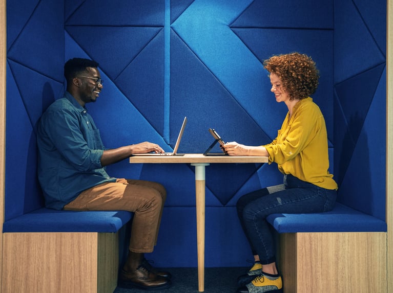 a man and a woman sitting at a table with a laptop