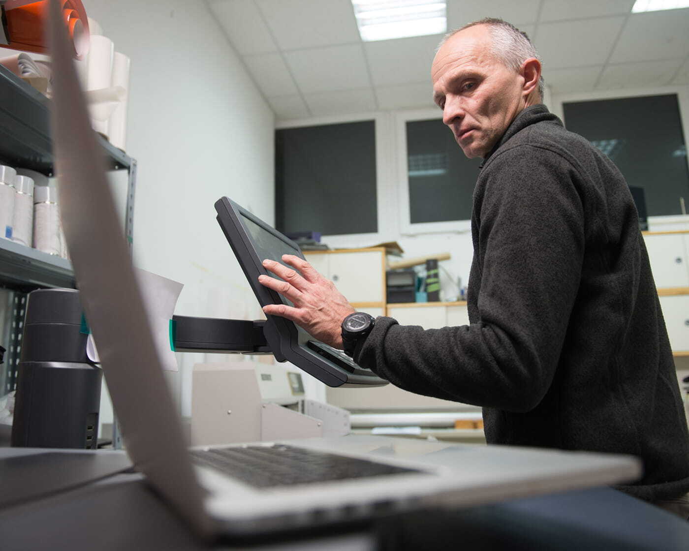 Employee working near an office printer, illustrating data breach risk from unsecured documents.