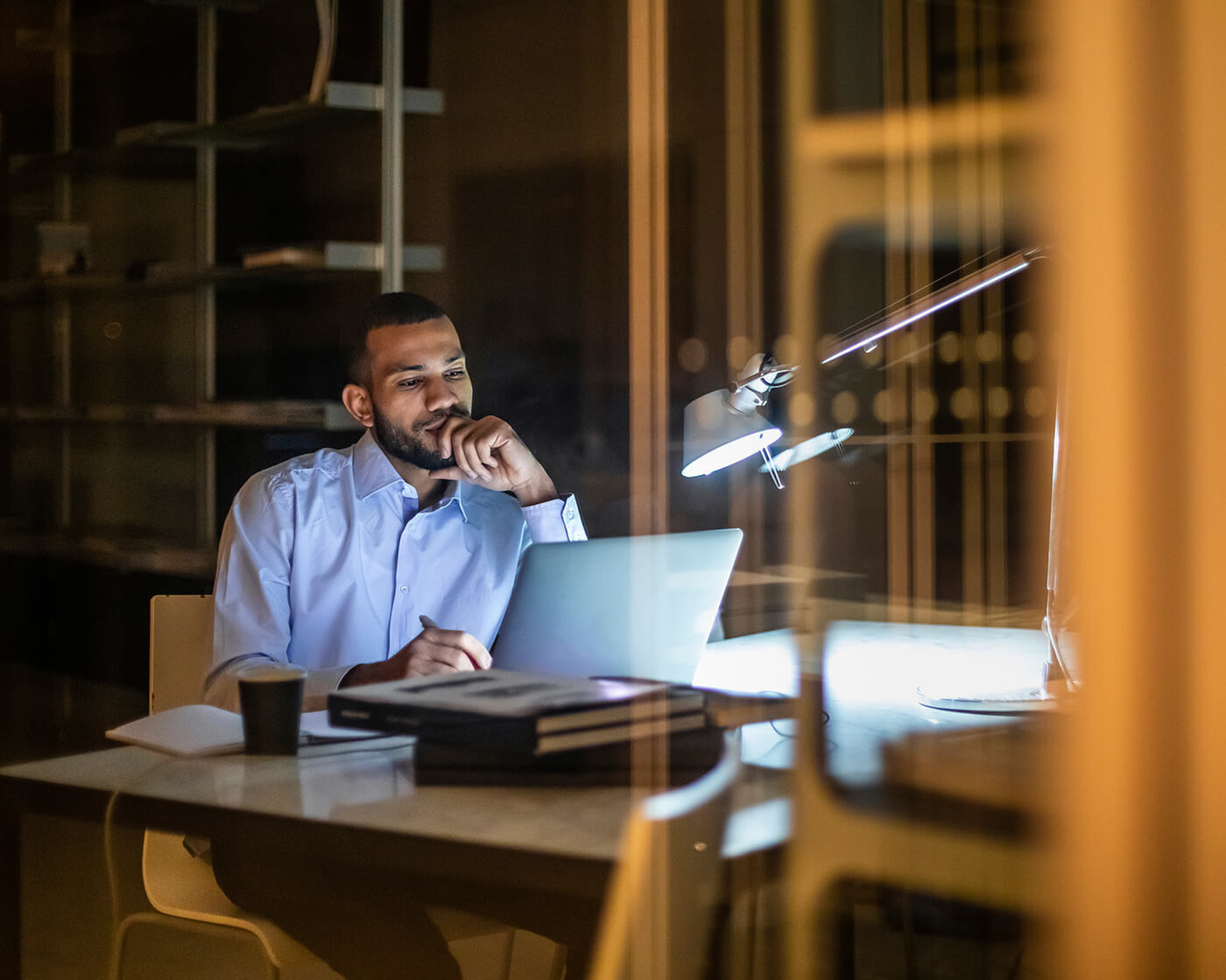 Man looking frustrated while working at a laptop in an office.