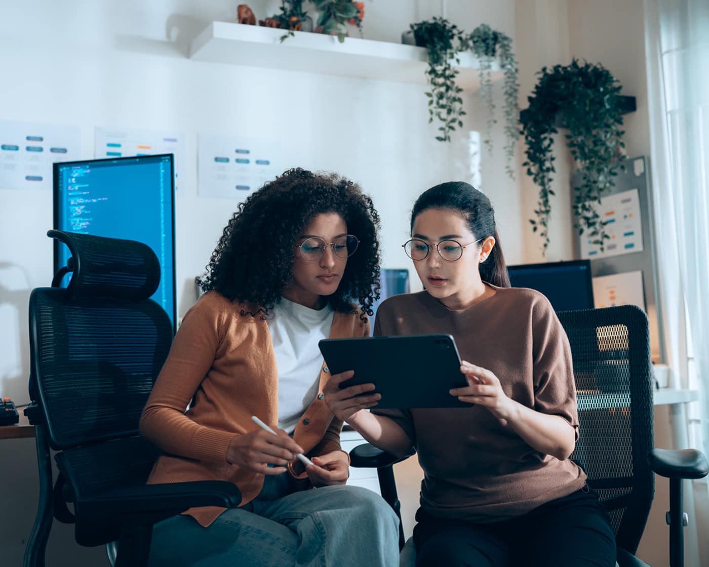 Two coworkers reviewing information on a tablet in a modern tech office.