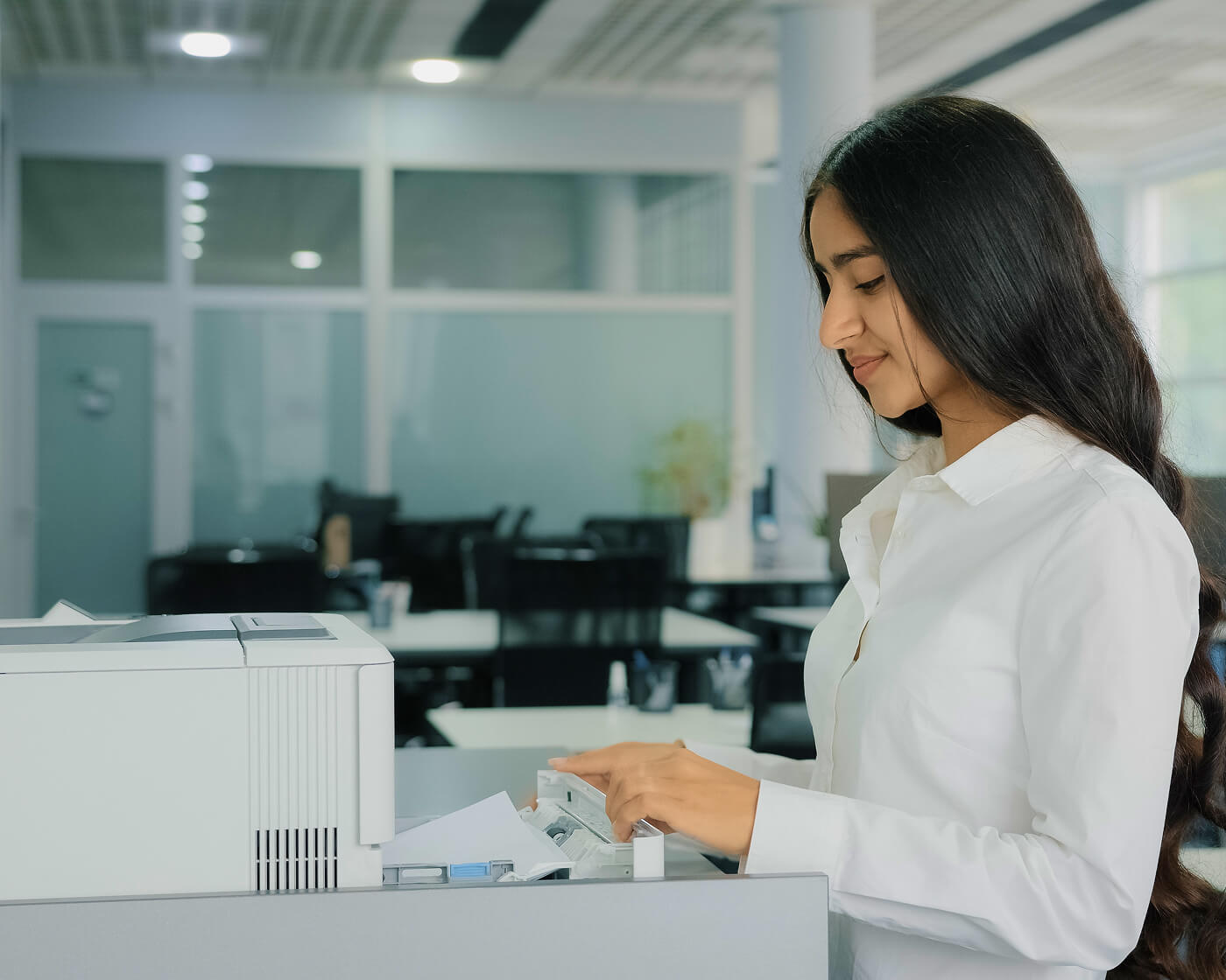 A woman at a printer in a corporate finance office.