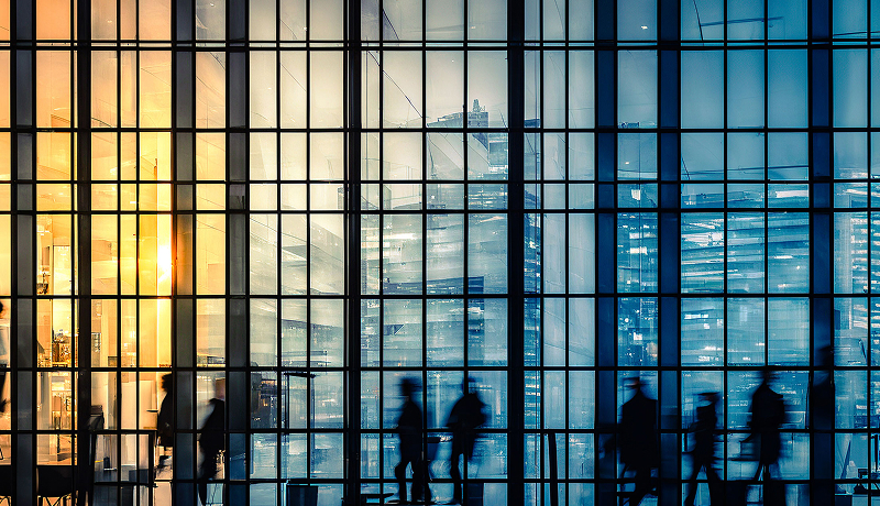 A business crowd in motion through windows.