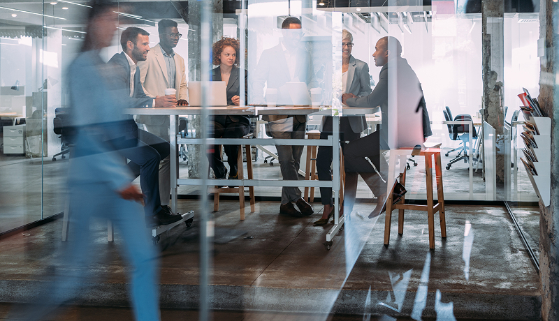 Motion-blurred employees walking through a modern office workspace.