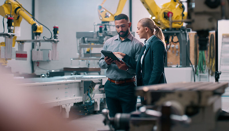 Engineers reviewing data on a tablet in a manufacturing plant.