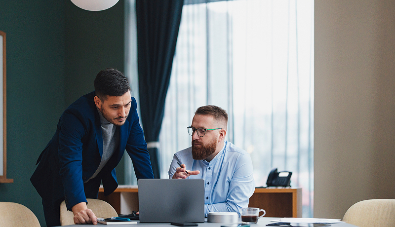 Two male employees strategizing together at a desk.