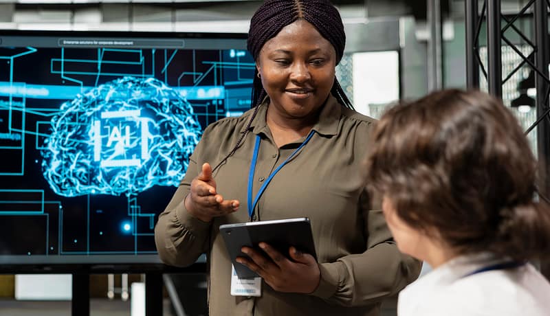 Woman engineer presenting AI technology on a tablet to a colleague.