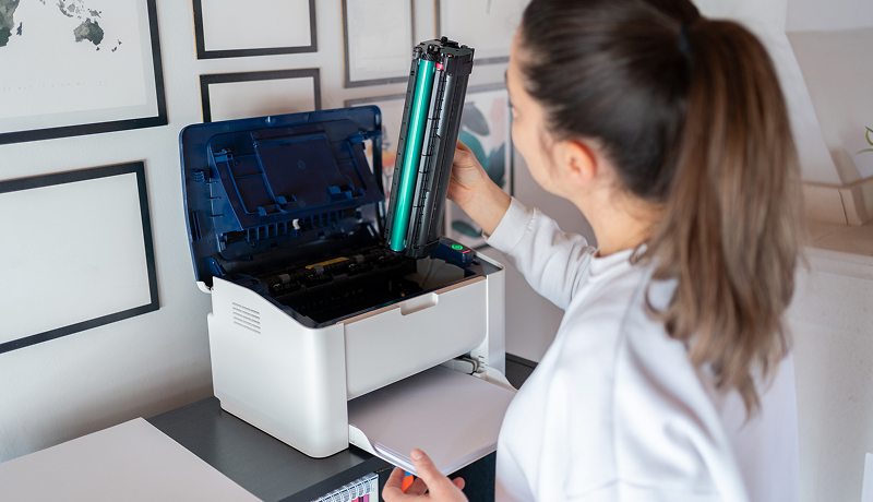 Woman replacing a toner cartridge in an office printer.