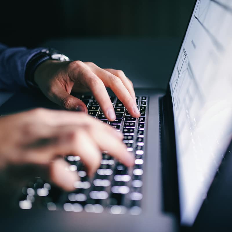 person-typing-on-laptop-keyboard-with-document-visible