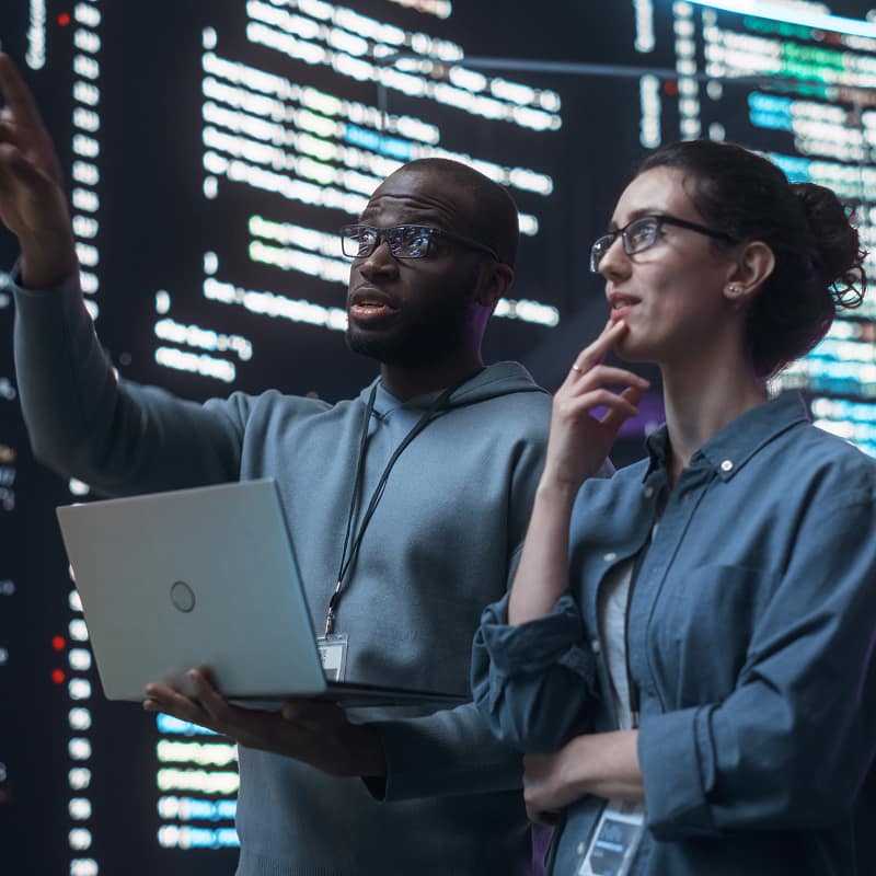 two-software-engineers-reviewing-code-on-laptop-in-server-room