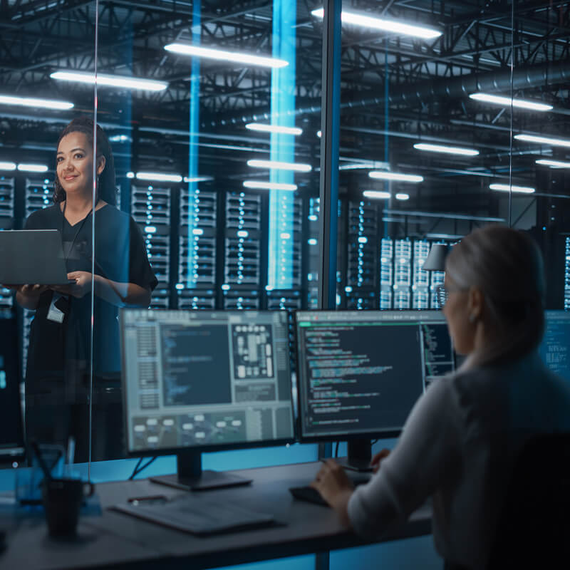 Women discussing data on monitors in a data center.