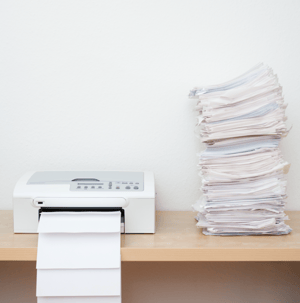 printer on desk with stack of paper