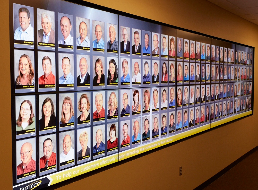 Image description: photo of Marco's video wall from Marco HQ in St. Cloud, MN featuring employee headshots