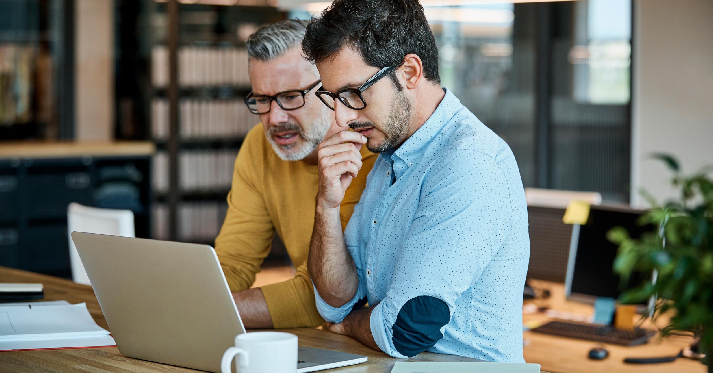 Two business partners compare different Microsoft licenses, with and without Microsoft Teams.