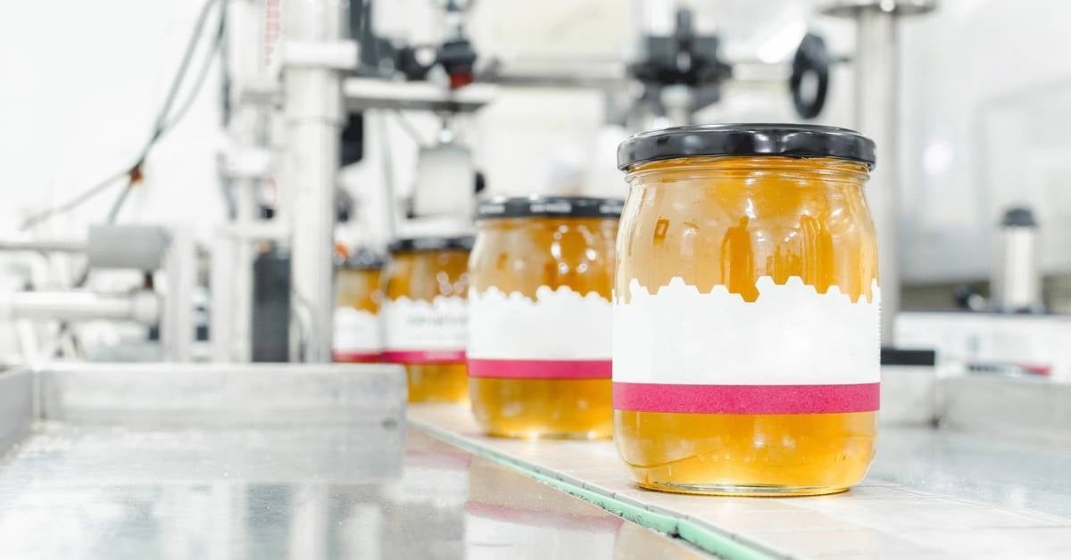 Honey jars moving along a production line.