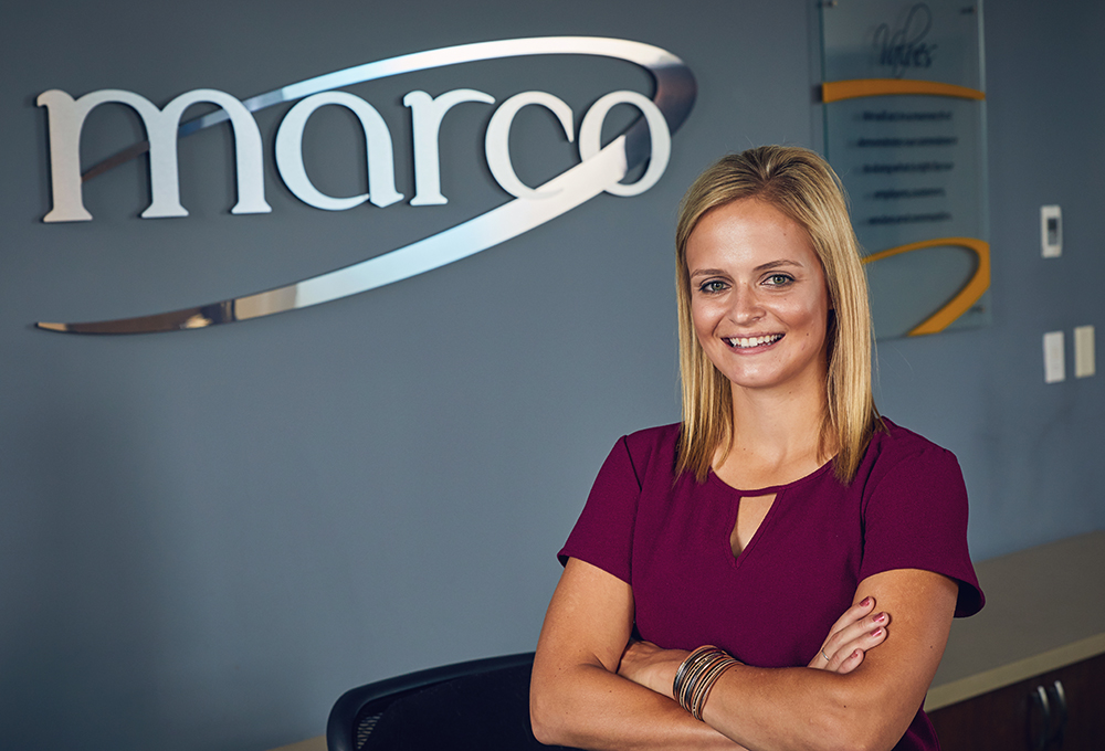 Employee in front of Marco Sign